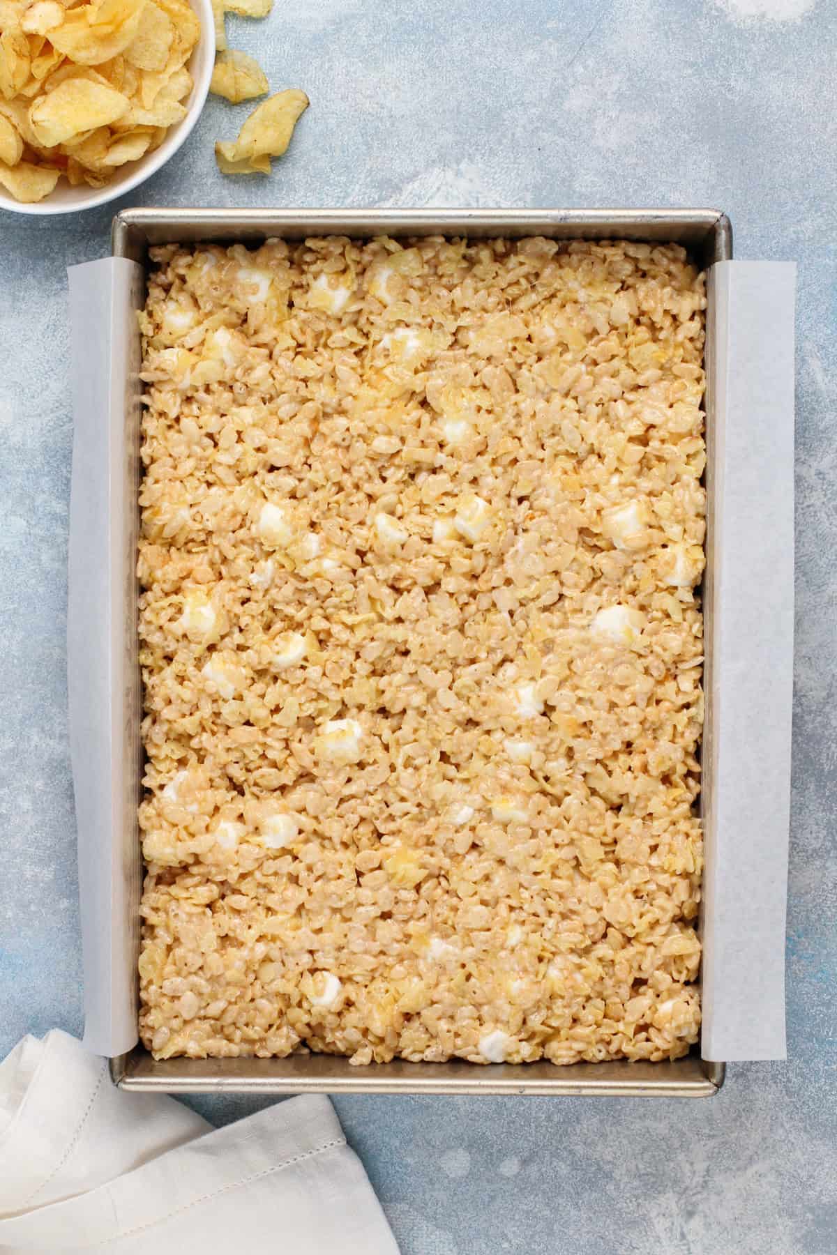 Potato chip rice krispie treat mixture pressed into a pan.