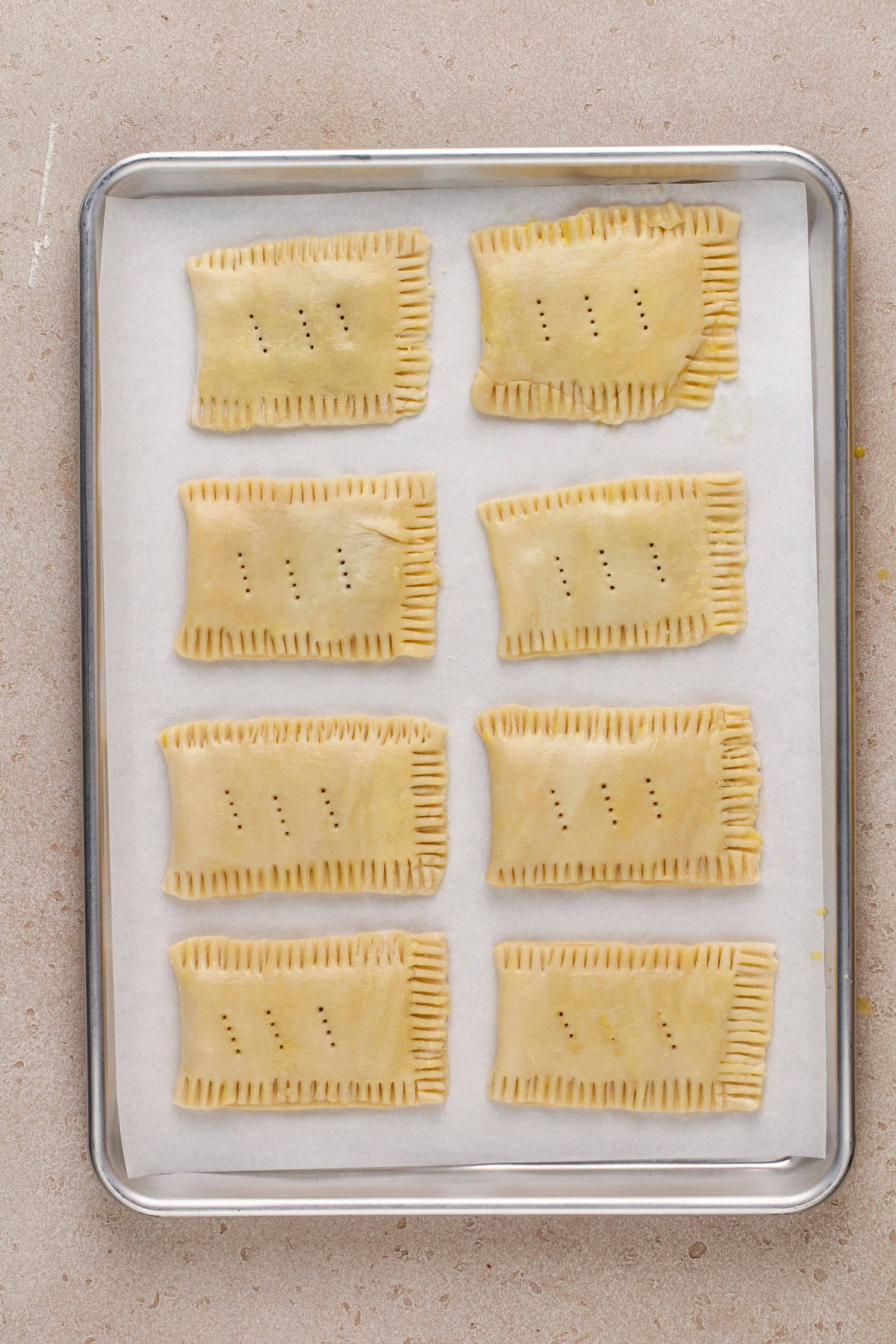 Unbaked homemade pop tarts on a parchment lined baking sheet.