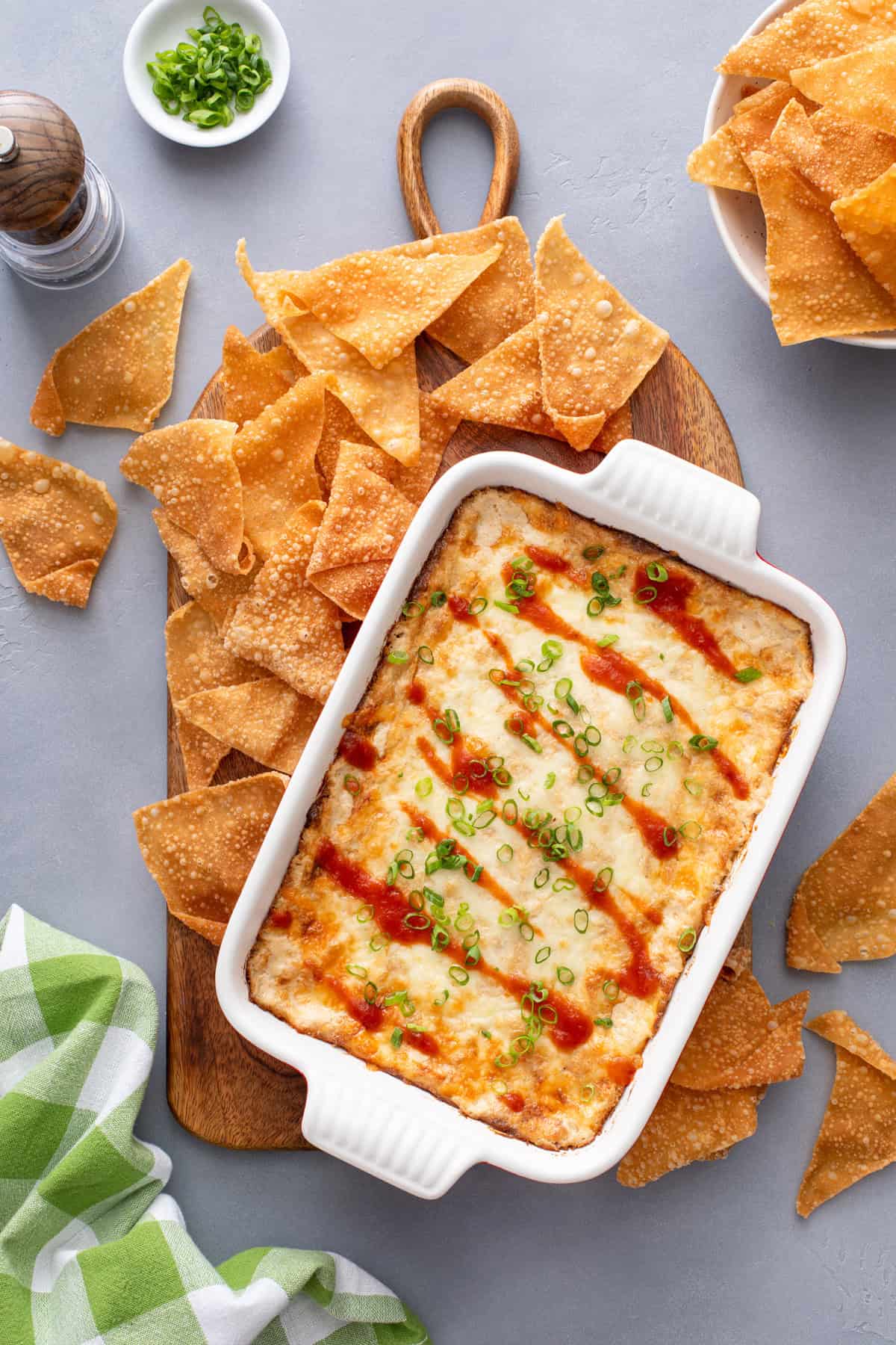 Overhead view of a baking dish of crab rangoon dip surrounded by wonton chips.