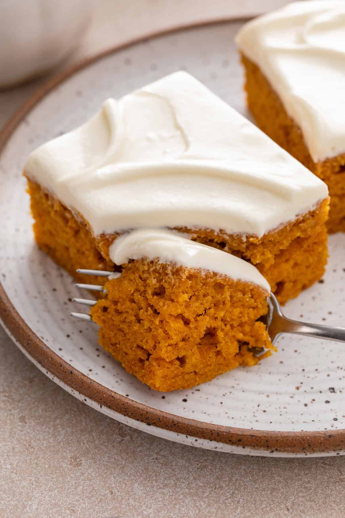 Fork cutting a bite from the corner of a plated pumpkin bar.