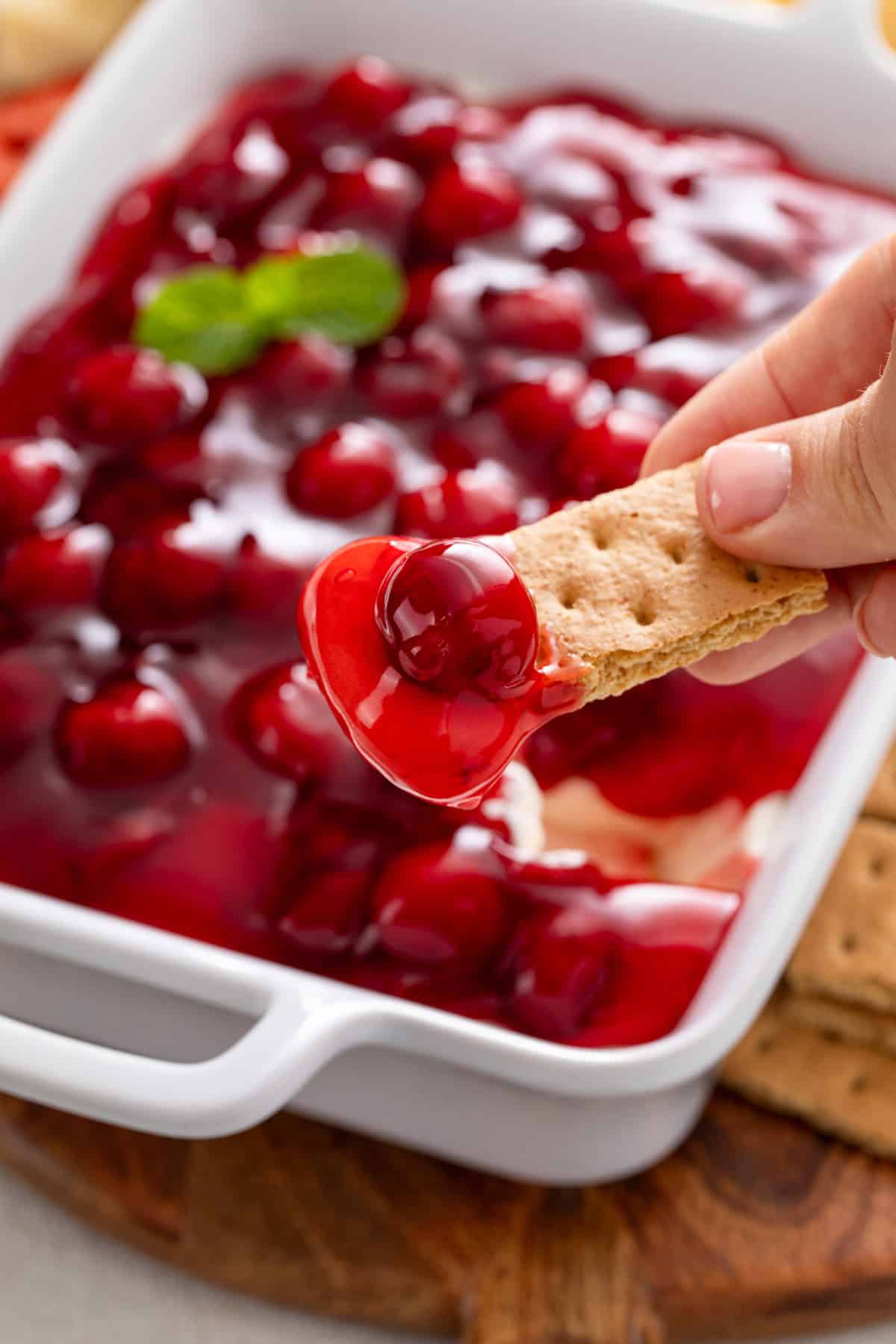 Graham cracker with cherry cheesecake dip on the end.