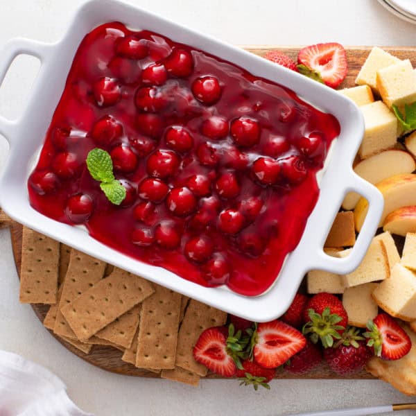 Serving dish of cherry cheesecake dip surrounded by dippers.