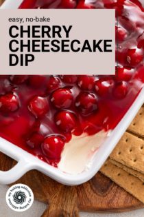 Serving dish of cherry cheesecake dip with some of the dip removed from the corner. Text overlay includes recipe name.