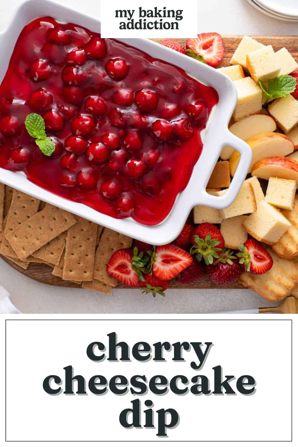 Cherry cheesecake dip in a serving dish on a wooden platter, surrounded by dippers such as cake cubes, apples, strawberries, and graham crackers. Text overlay includes recipe name.