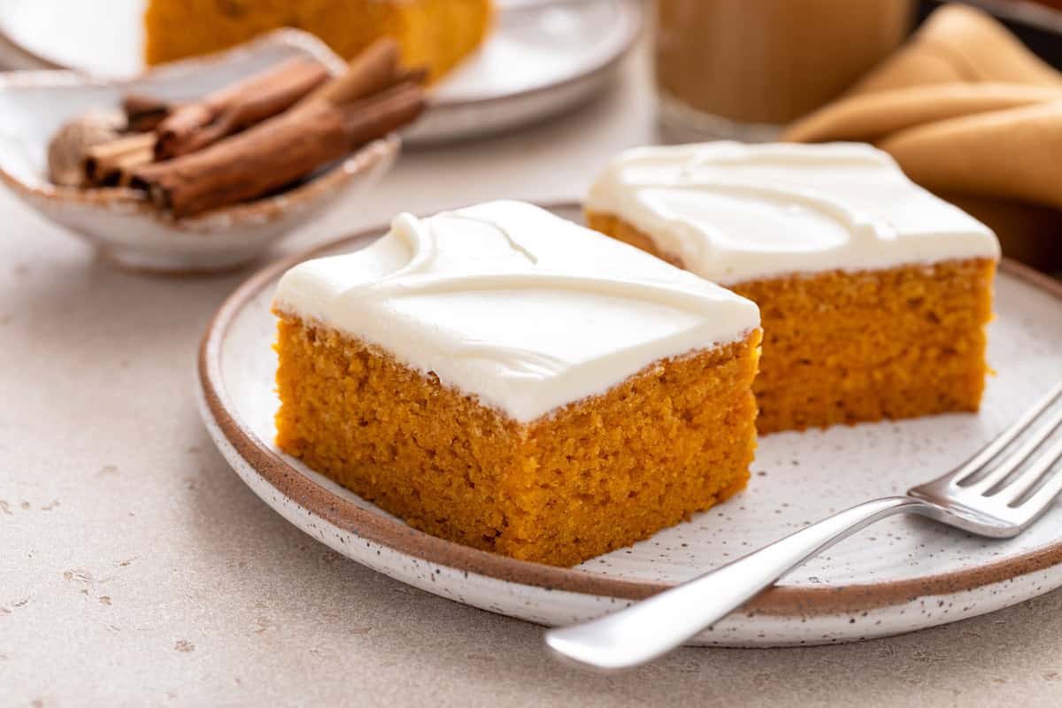 Close up of two pumpkin bars next to a fork on a plate.