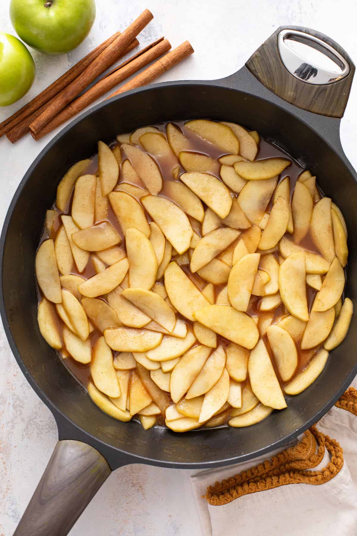 Cooked cinnamon apples in a black skillet.