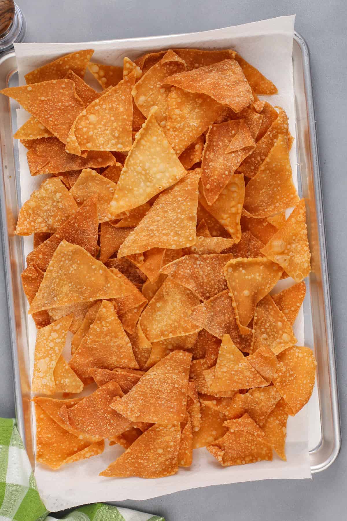 Fried wonton chips cooling on a sheet pan.