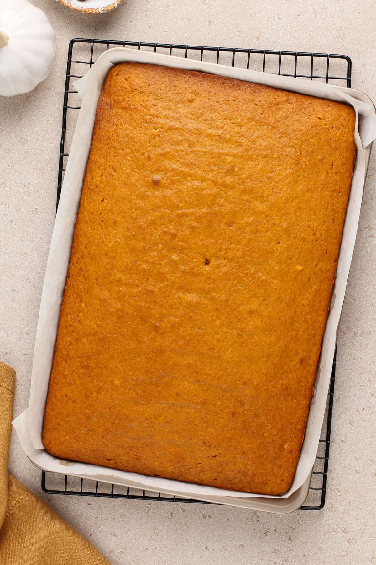 Baked pumpkin bars in a jelly roll pan, cooling on a wire rack.