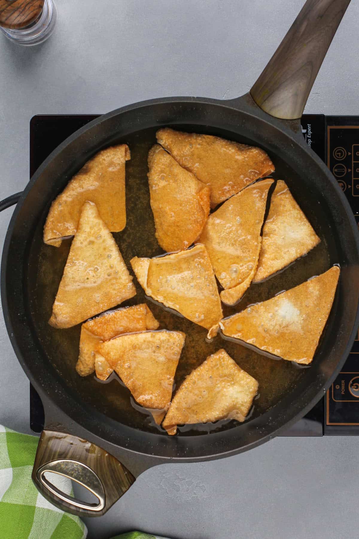 Wonton chips being deep fried in a skillet.