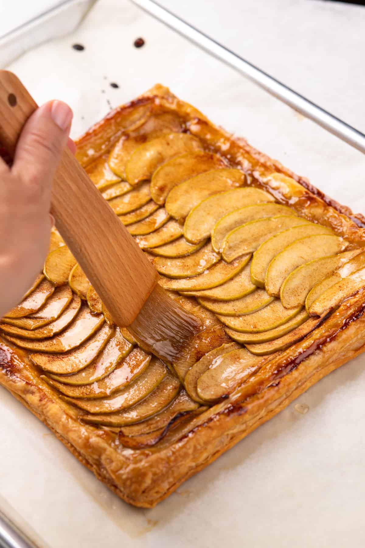 Brushing glaze over a baked puff pastry apple tart.