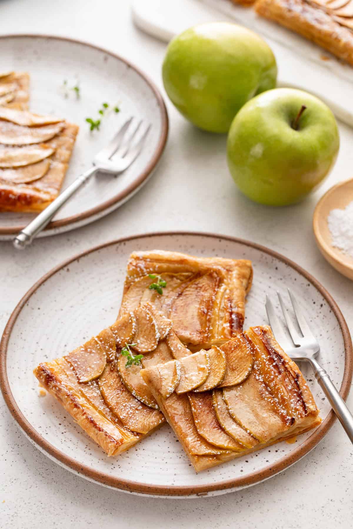 Three slices of puff pastry apple tart next to a fork on a plate.