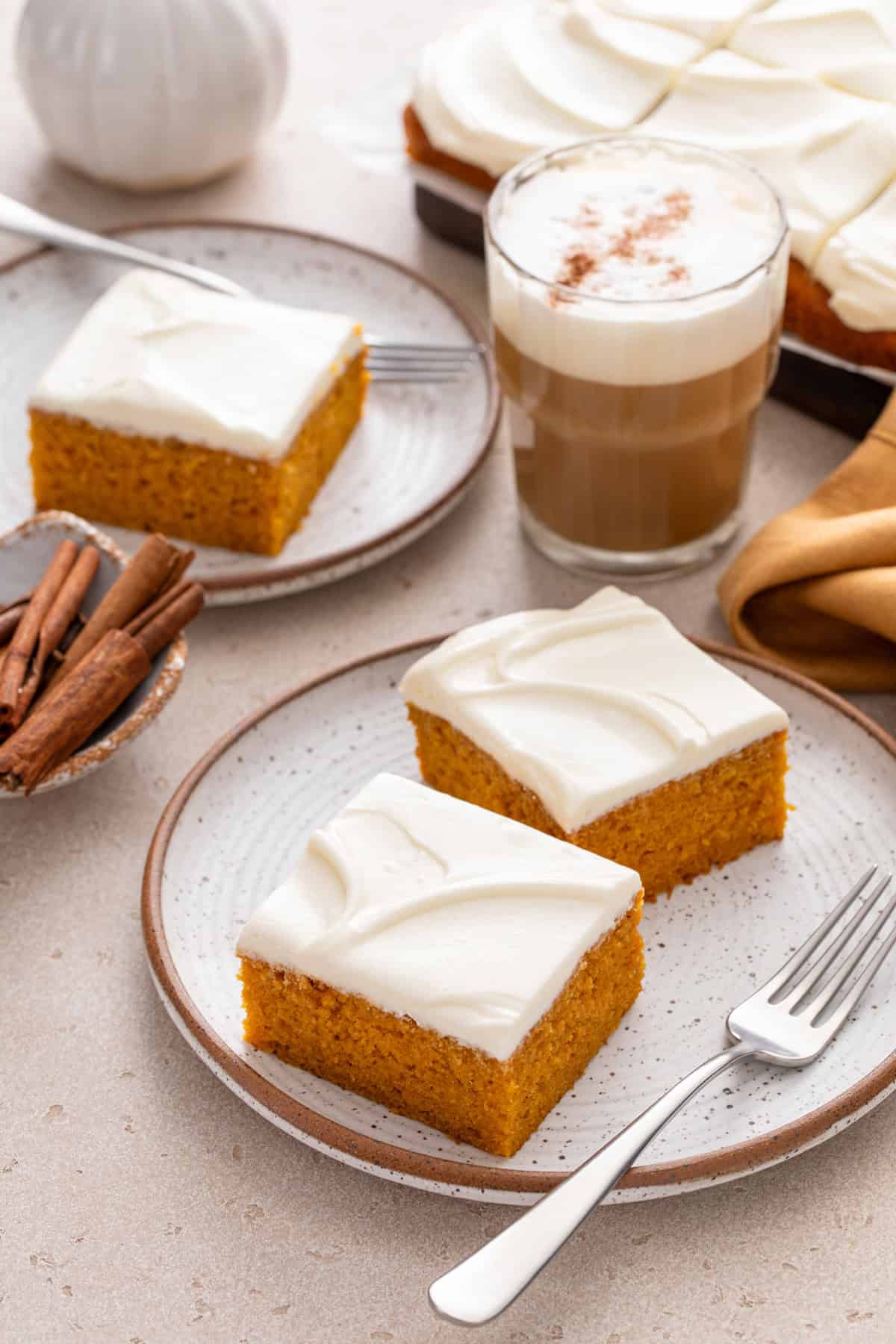 Two plates of pumpkin bars next to an iced coffee.