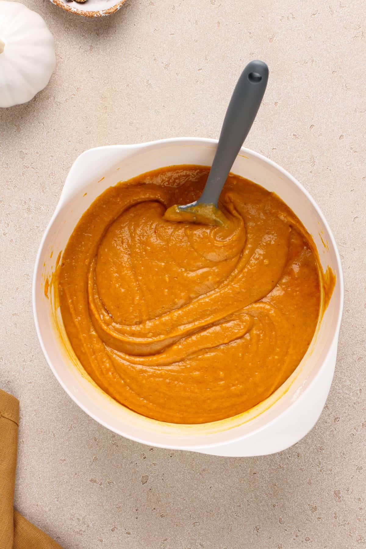 Batter for pumpkin bars stirred together in a white mixing bowl.