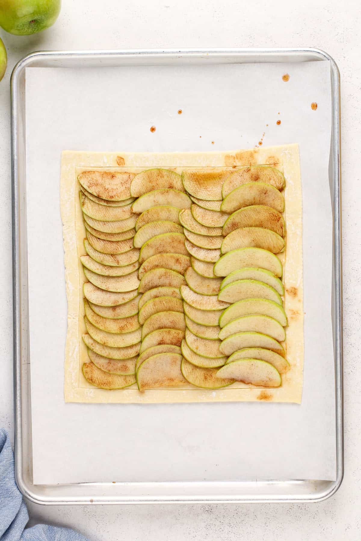 Unbaked puff pastry apple tart on a sheet pan, ready to go in the oven.