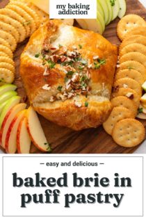 Baked brie in puff pastry on a wooden board surrounded by crackers and apples. Text overlay includes recipe name.