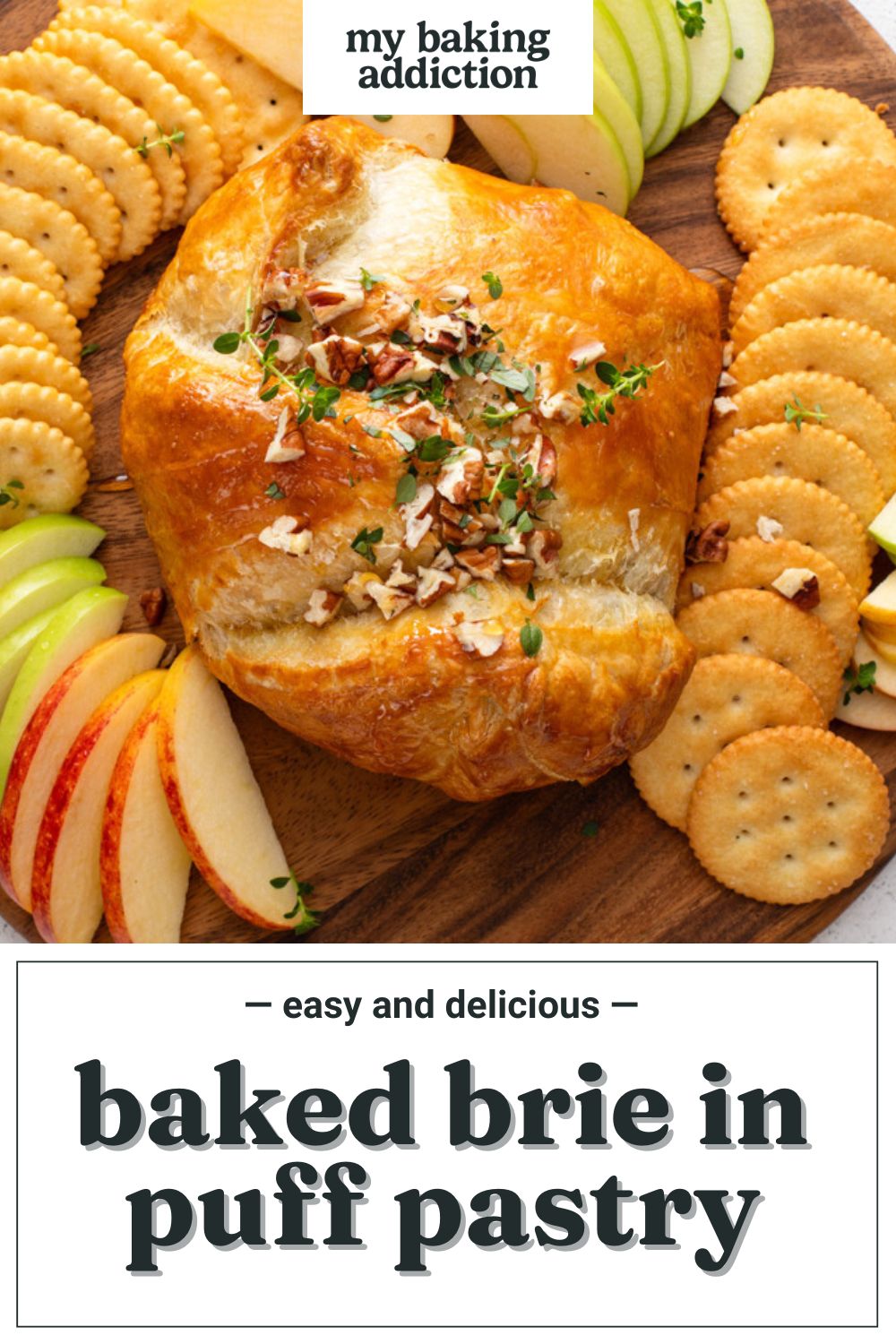 Baked brie in puff pastry on a wooden board surrounded by crackers and apples. Text overlay includes recipe name.