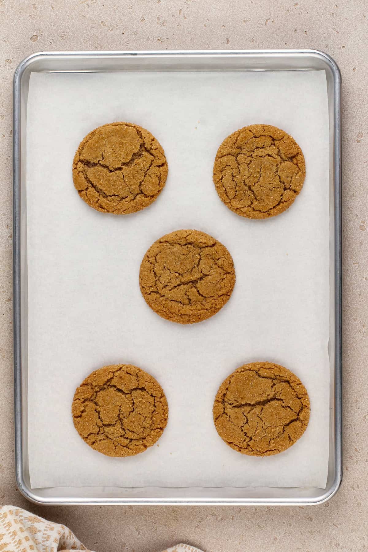 Five cinnamon brown sugar cookies baked on a lined baking sheet.