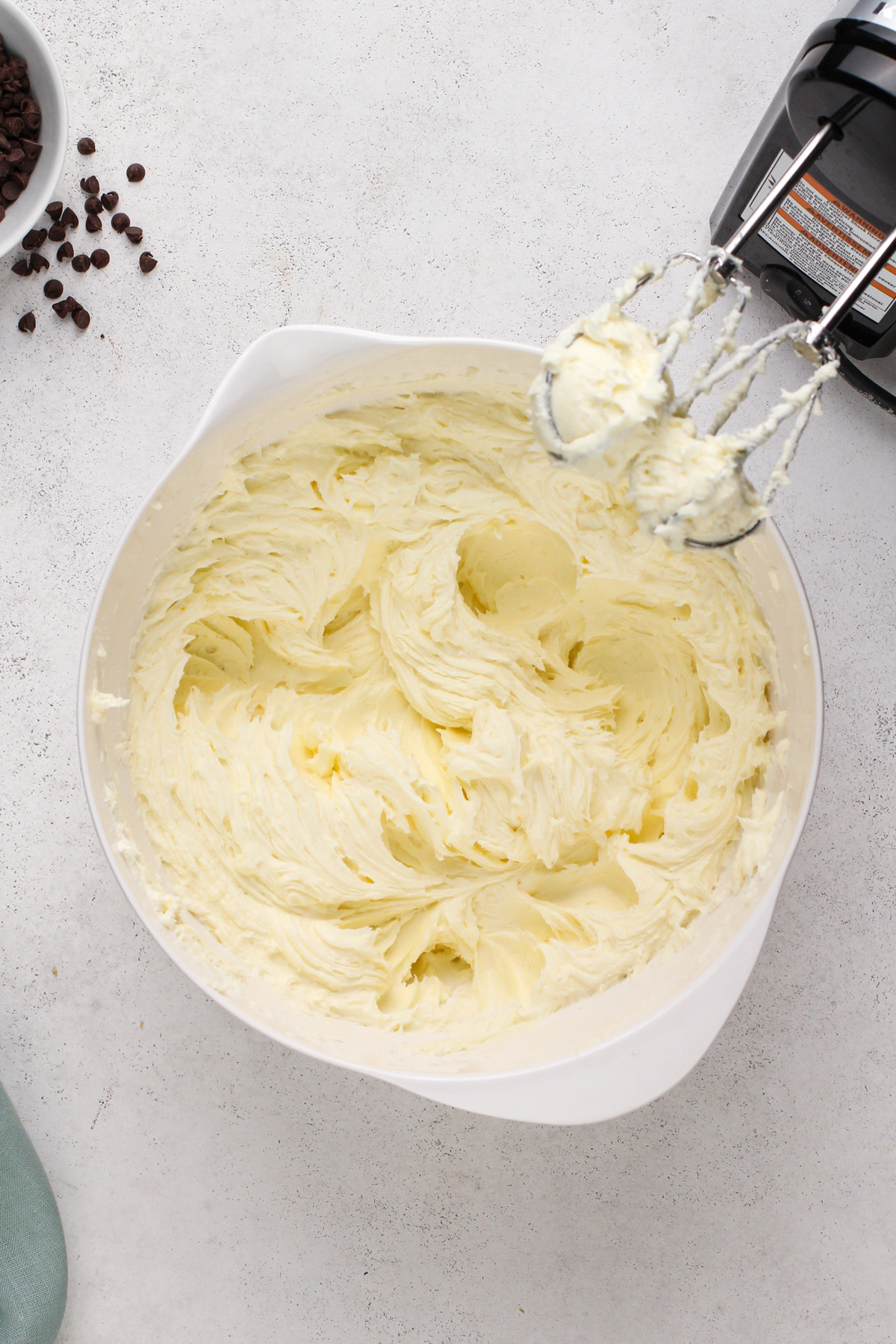 Cream cheese beaten with sugar and flour in a white bowl.