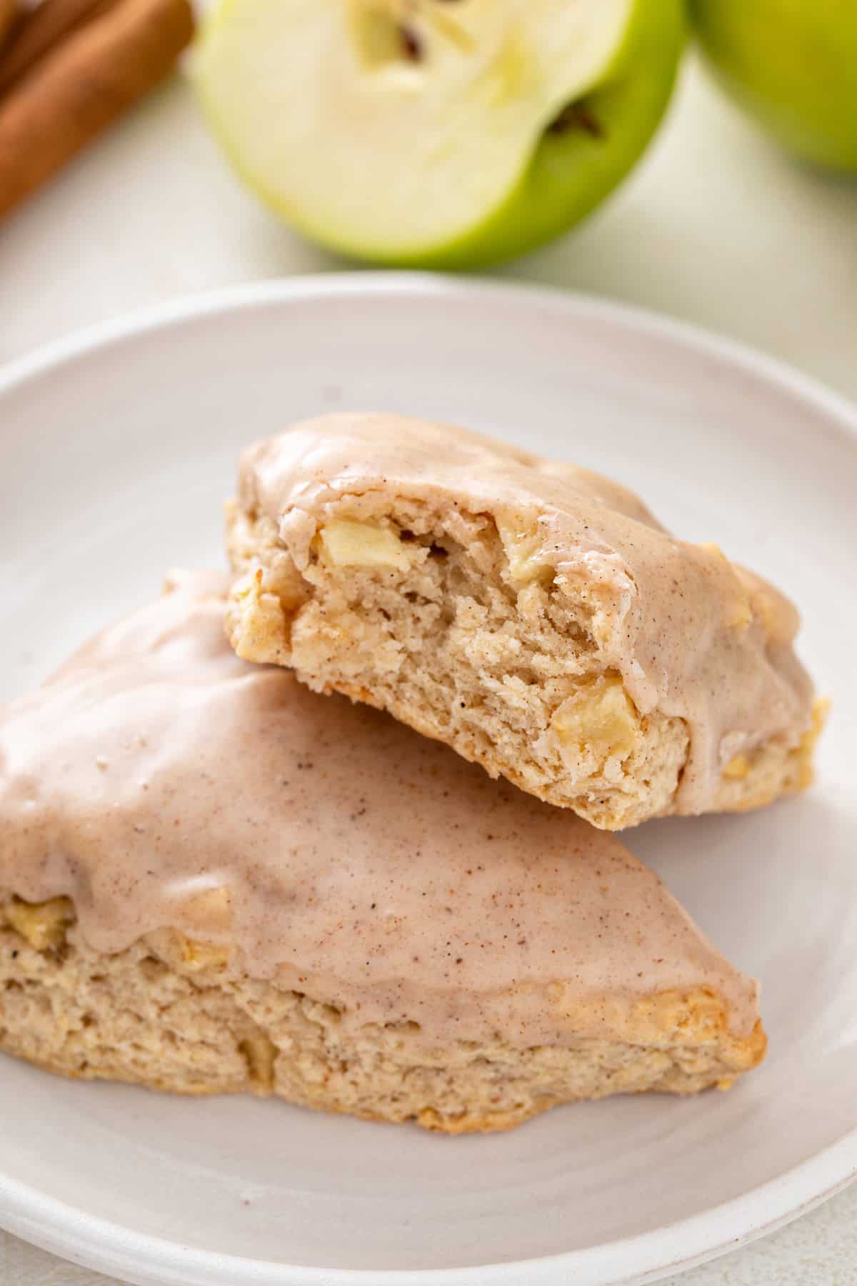 Close up of two apple scones on a plate, with a bite taken from one of them.