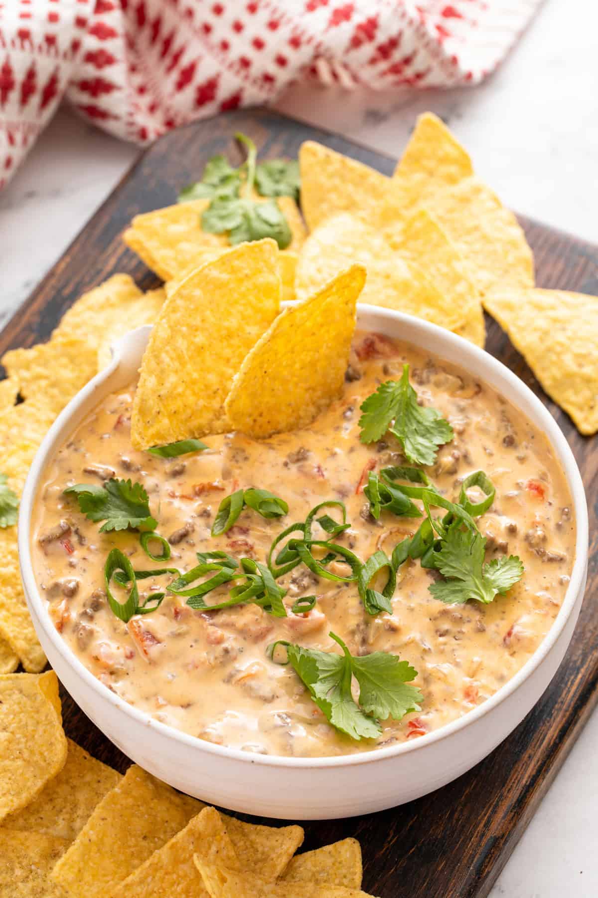 Tortilla chips in a bowl of rotel dip garnished with cilantro.