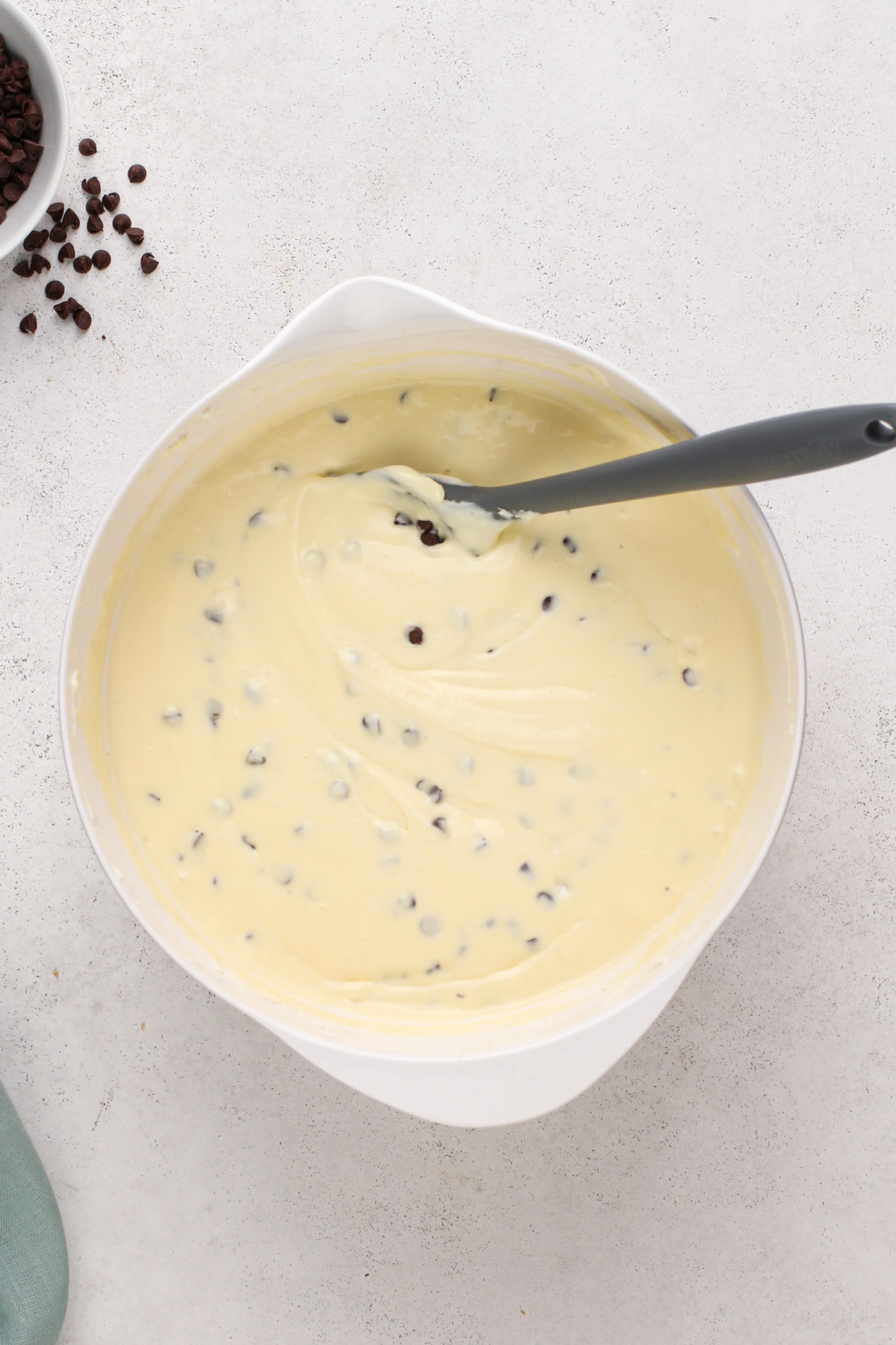 Chocolate chip cheesecake batter in a white bowl.