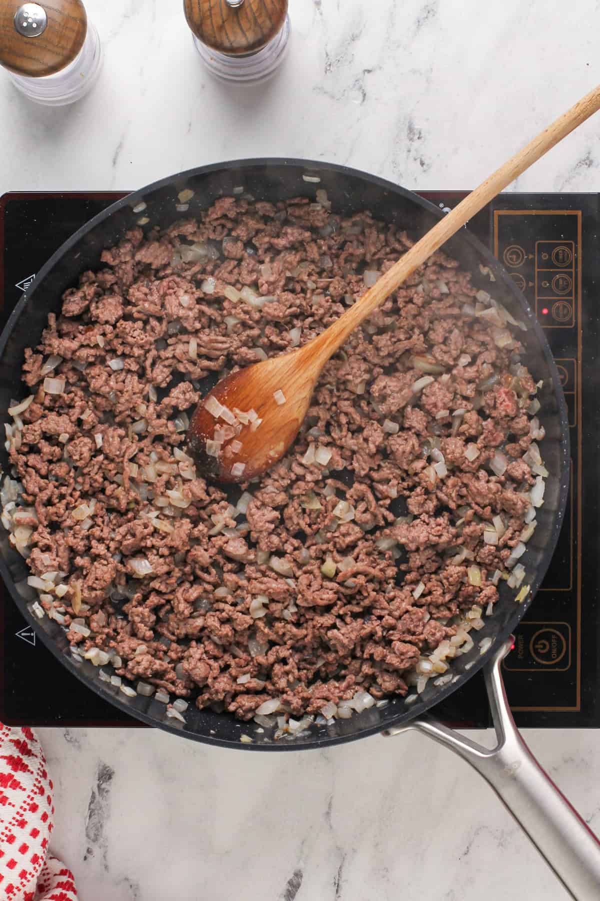 Ground beef and onions cooking in a skillet.