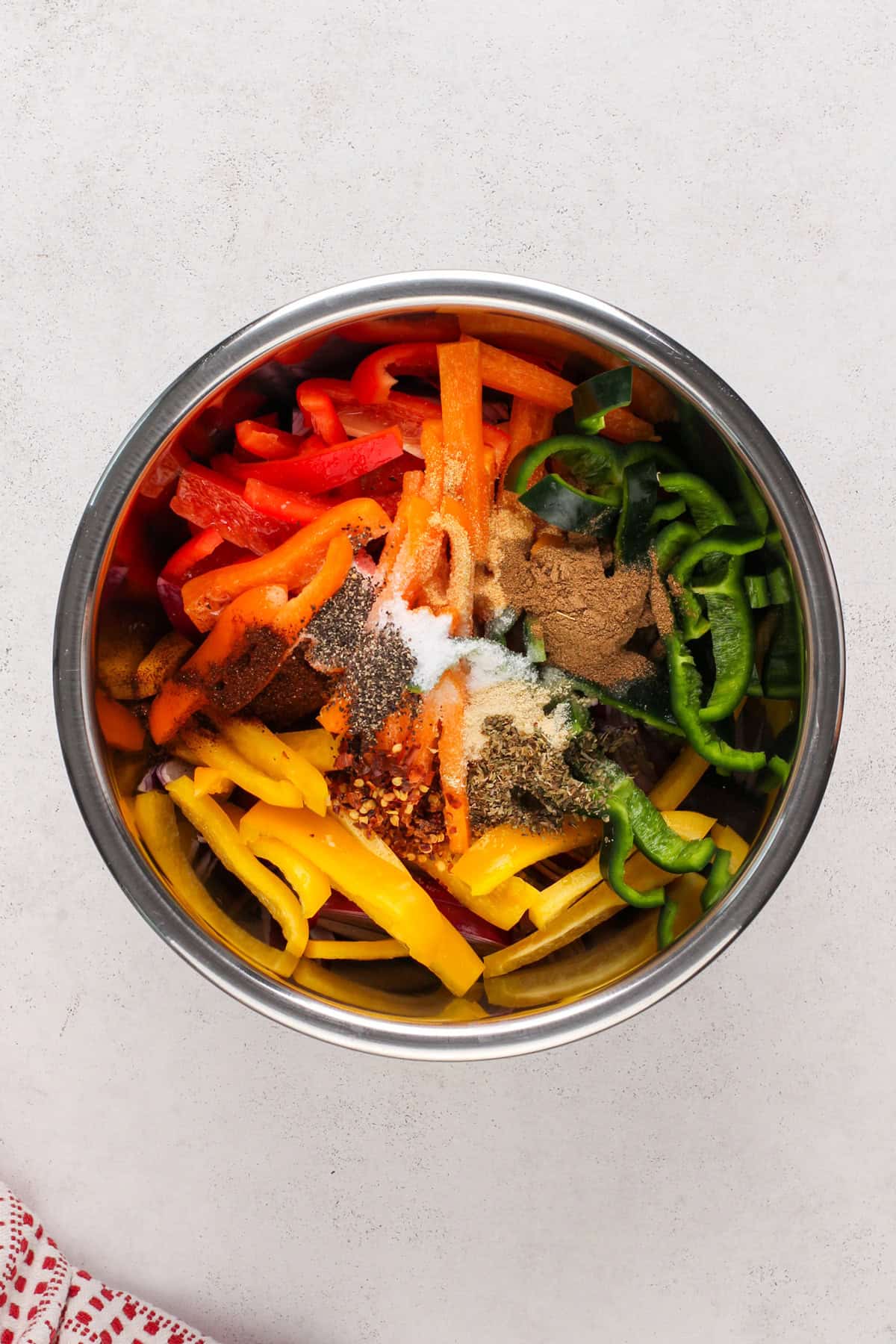 Ingredients for sheet pan fajitas in a metal bowl.