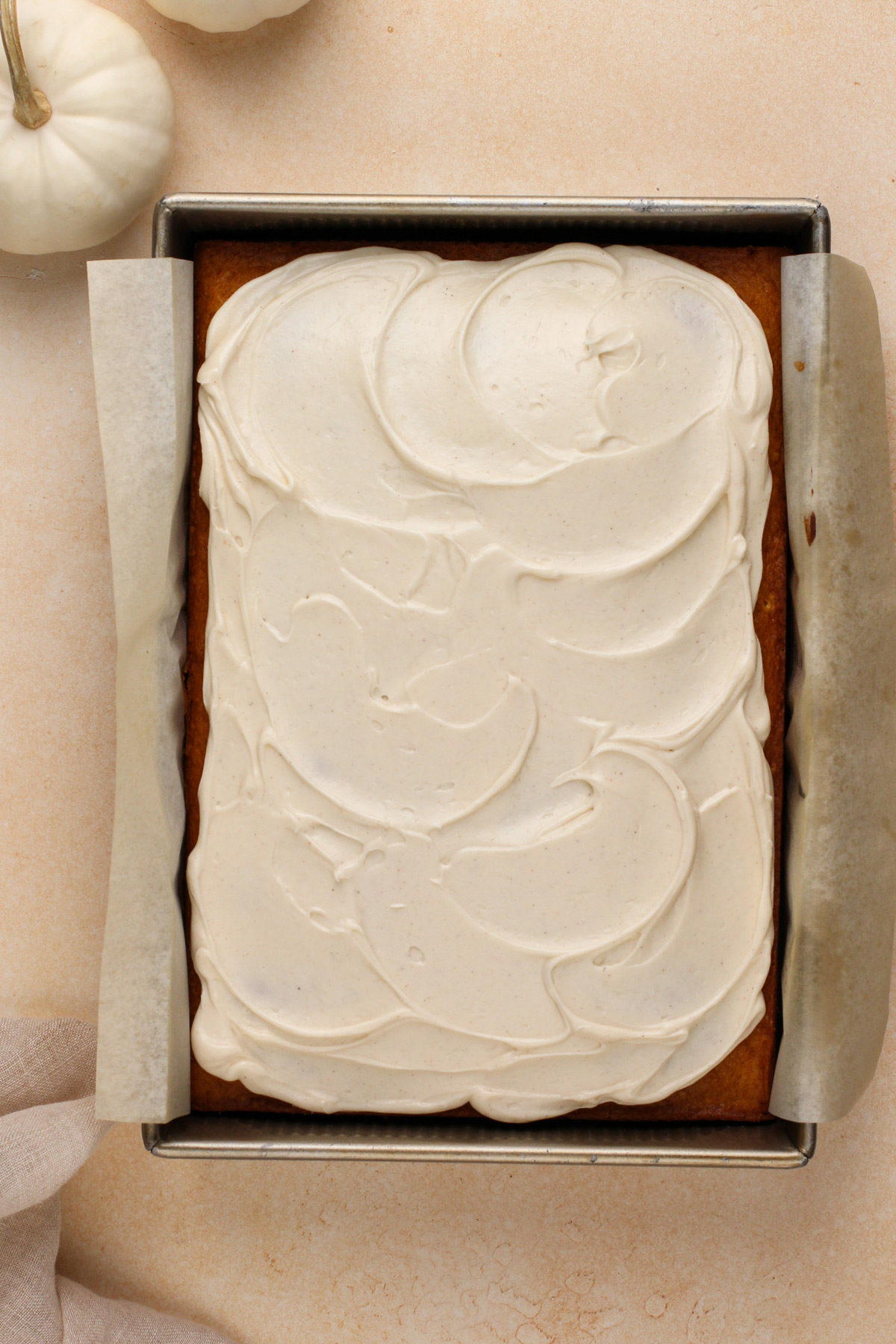 Cream cheese frosting spread over a pumpkin sheet cake.