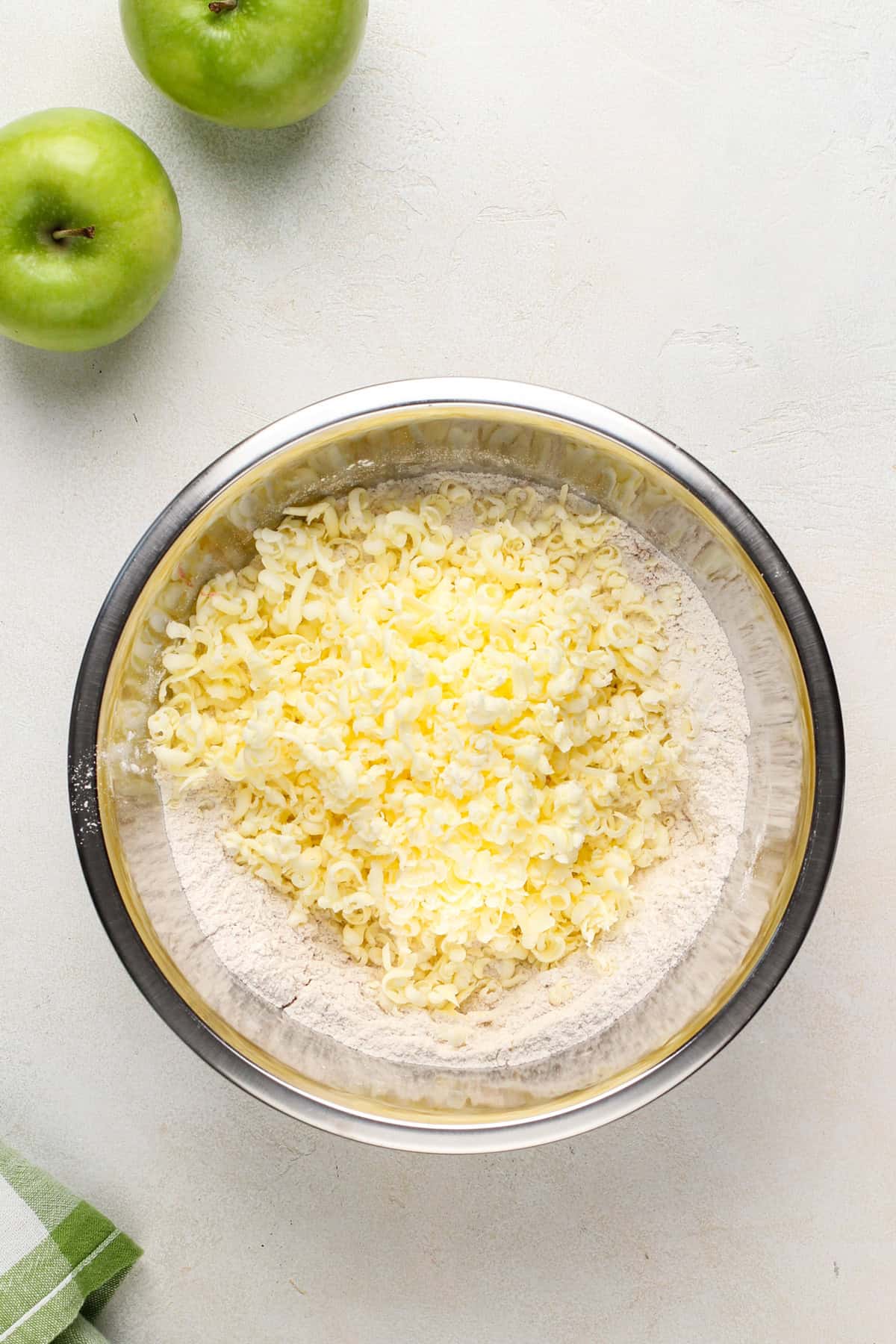 Grated butter in a bowl on top of flour.