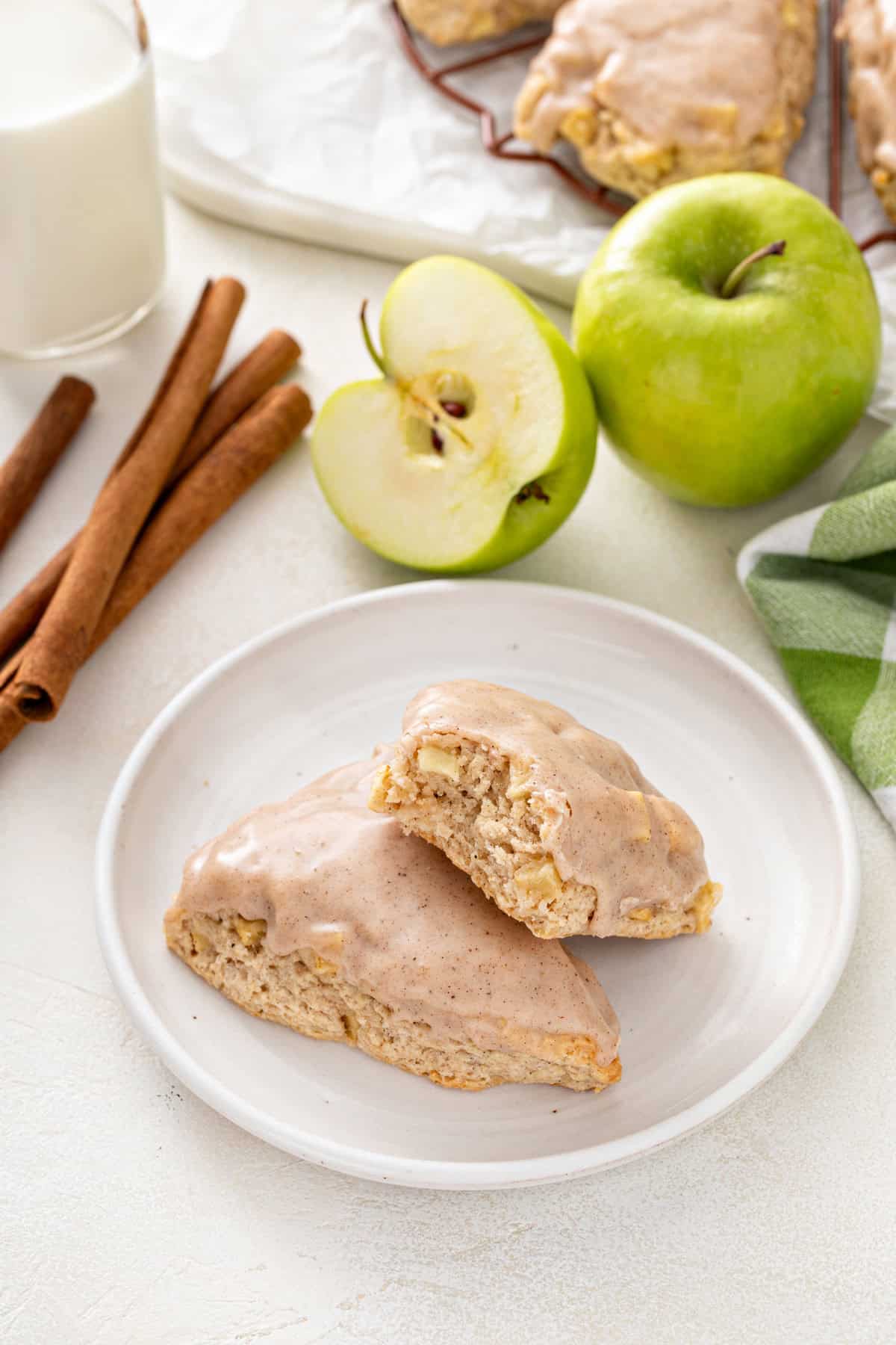 Half apple muffin and whole apple muffin on a white plate.