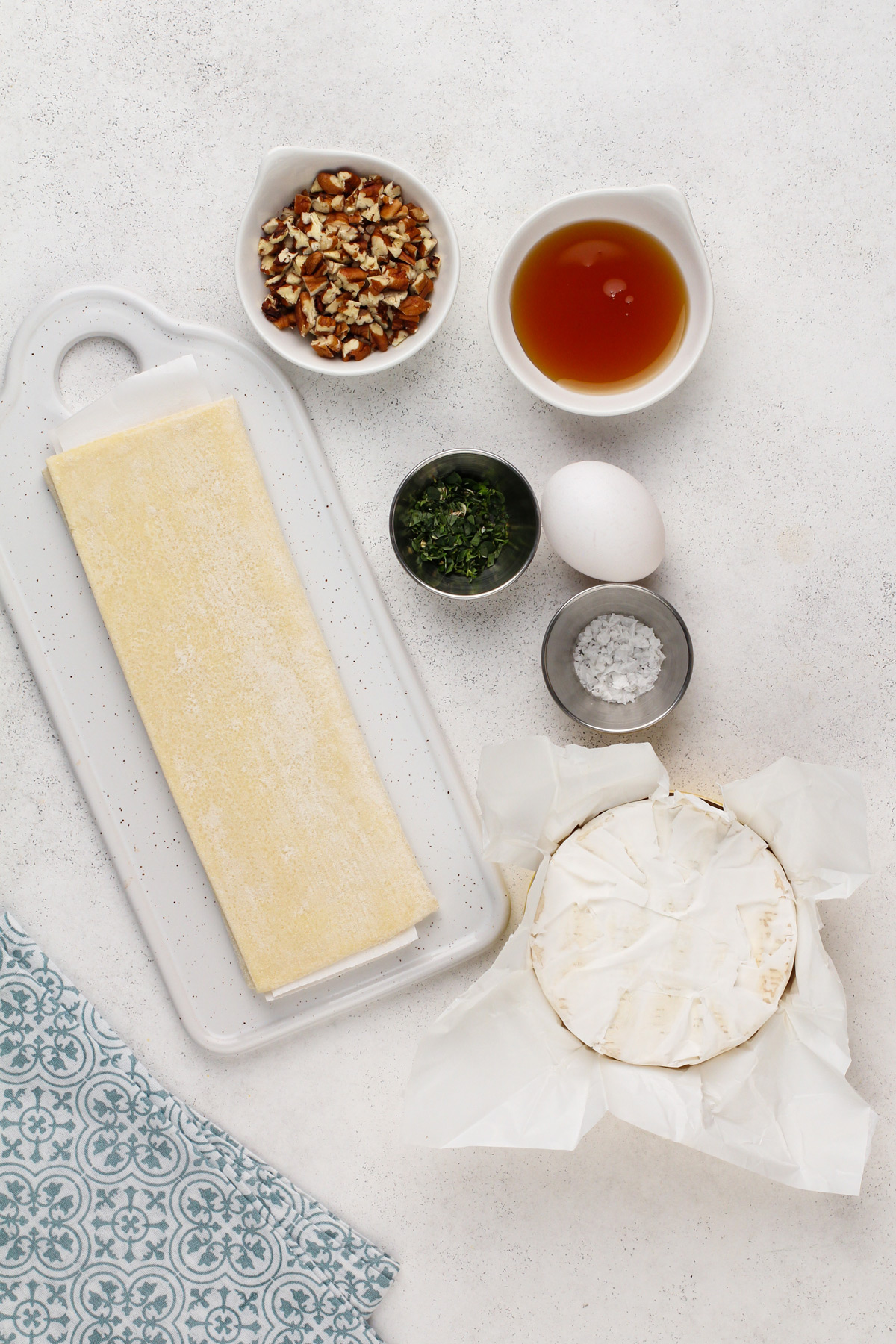 Ingredients for baked brie in puff pastry arranged on a countertop.