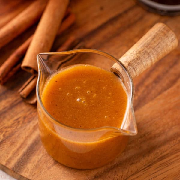 Jar of pumpkin coffee syrup on a wooden board.