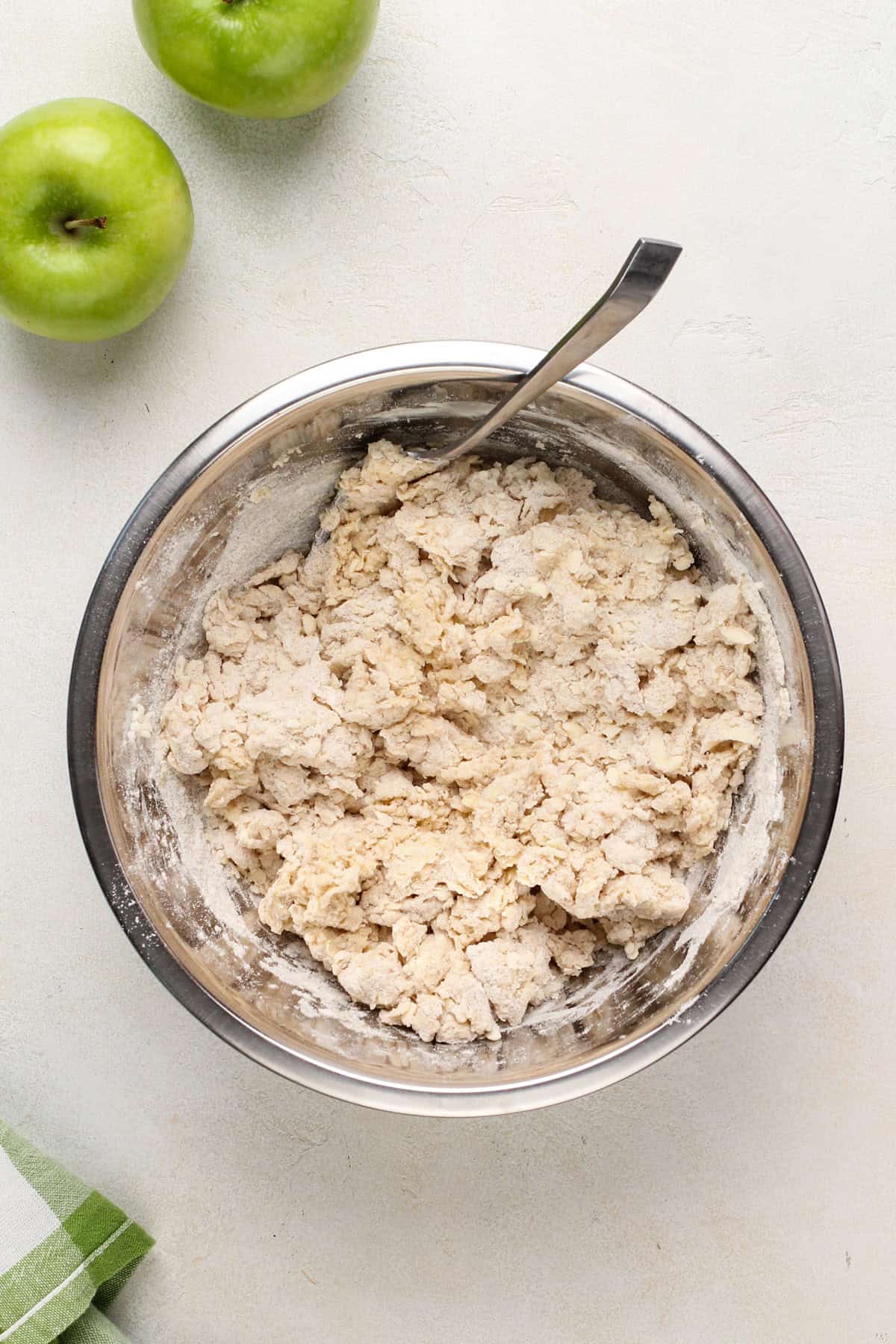 Dough for apple scones stirred together with a fork in a metal bowl.