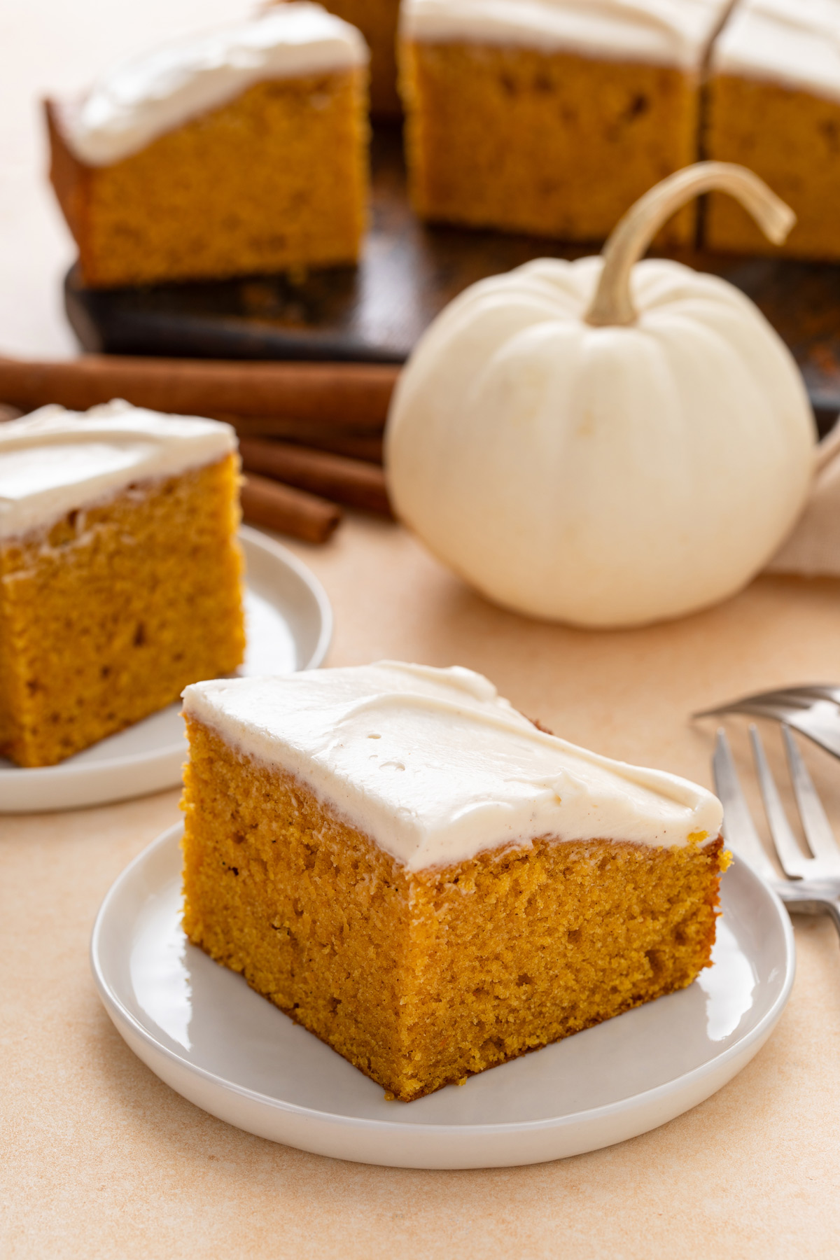 Plated slices of pumpkin sheet cake topped with cream cheese frosting.