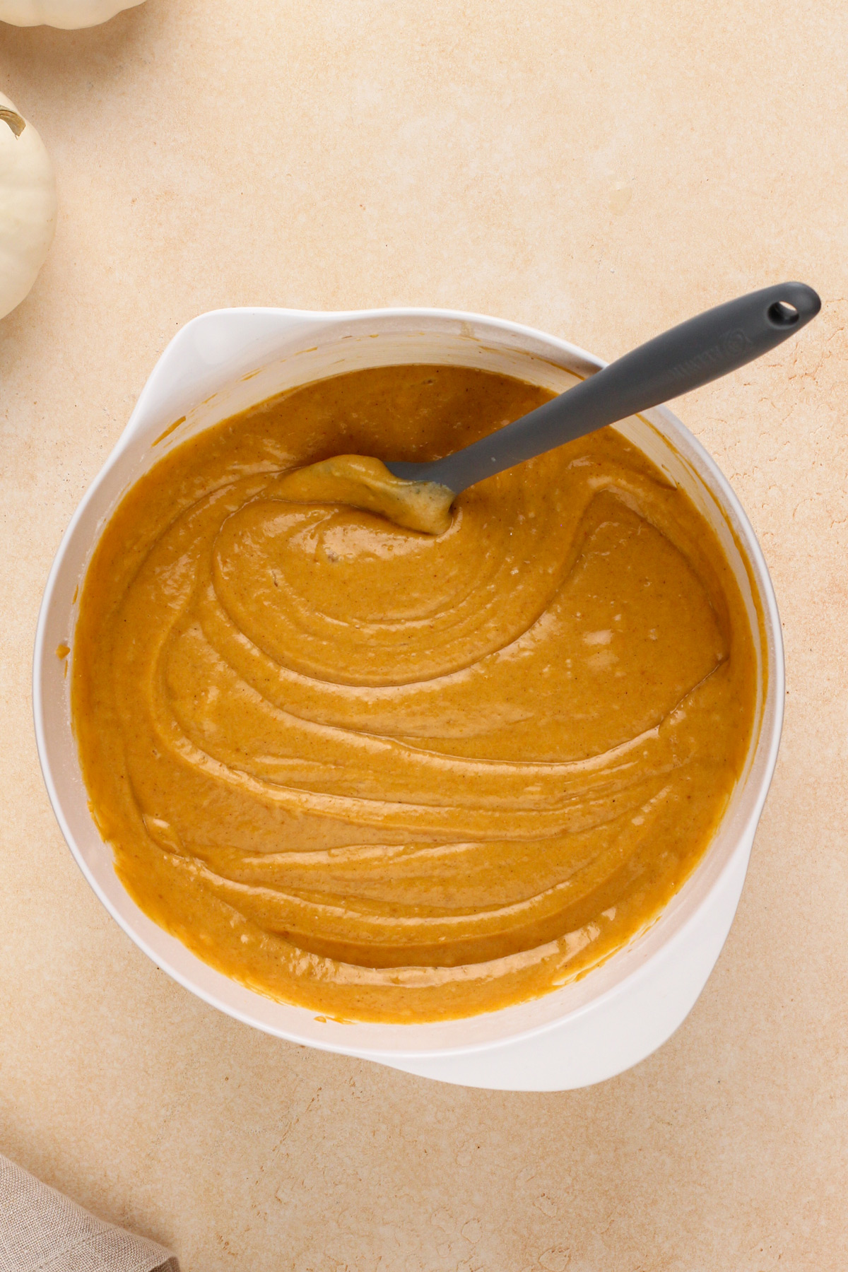 Pumpkin cake batter mixed in a white bowl.