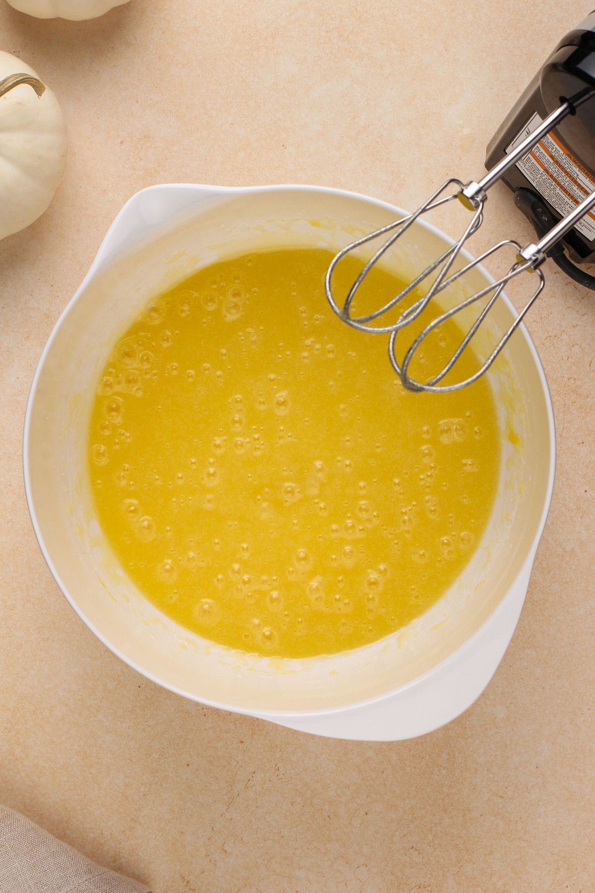 Wet ingredients for pumpkin cake mixed in a white bowl.