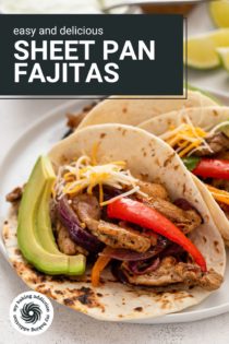 Close up of assembled sheet pan chicken fajitas topped with cheese and avocado on a plate. Text overlay includes recipe name.