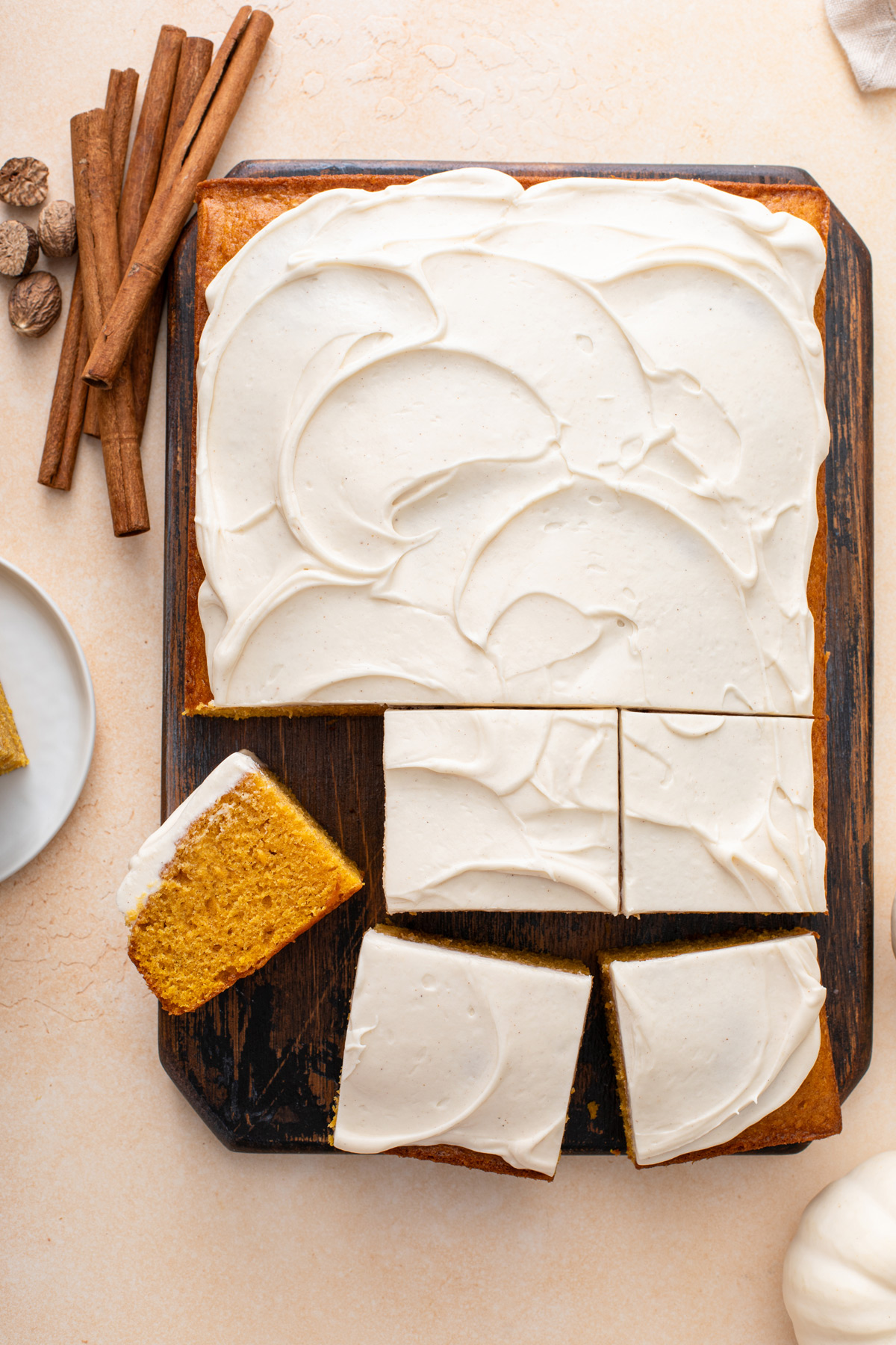 Sliced pumpkin cake topped with cream cheese frosting.