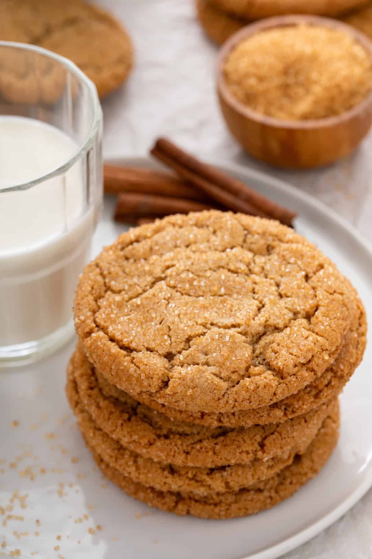 Brown sugar cookies stacked next to a glass of milk on a white plate.