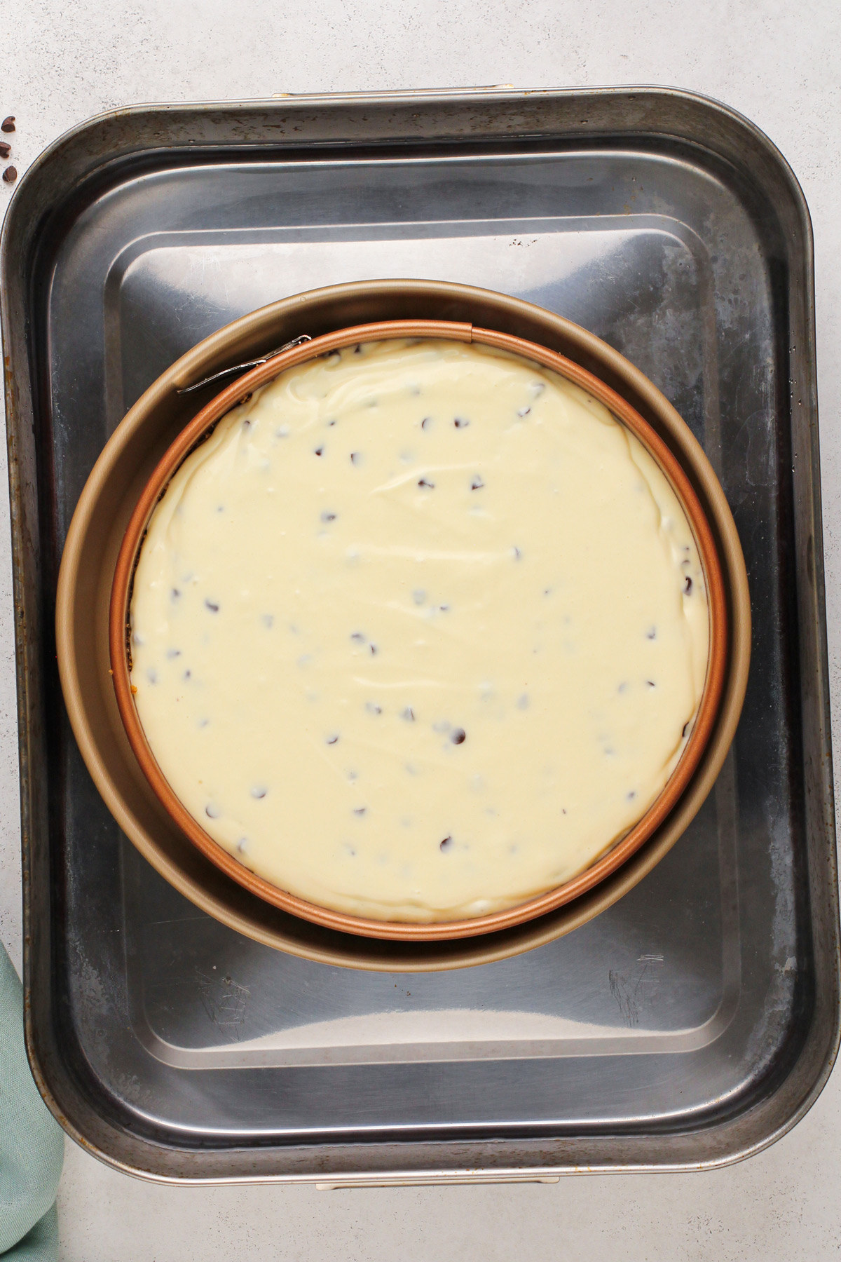 Unbaked chocolate chip cheesecake in a water bath, ready to go in the oven.