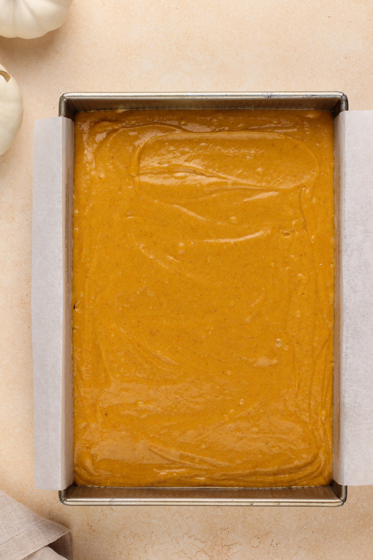 Pumpkin cake batter spread into a cake pan, ready to go in the oven.