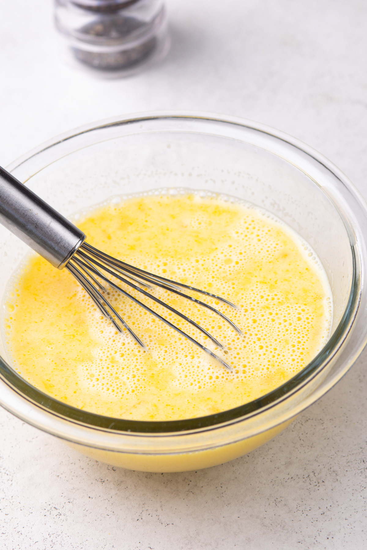 Eggs and lemon juice whisked together in a bowl.