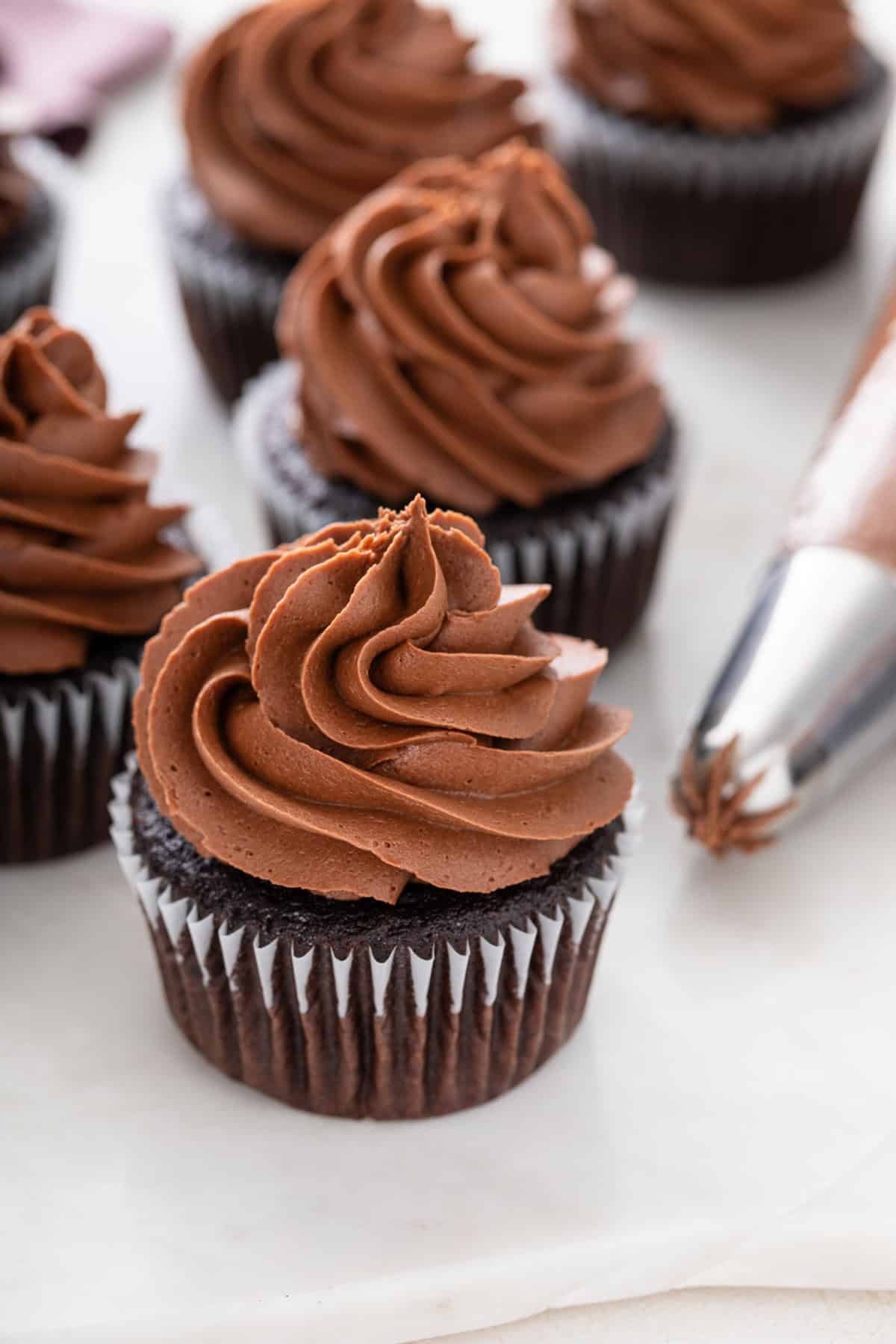 Chocolate buttercream frosting piped on top of a chocolate cupcake.