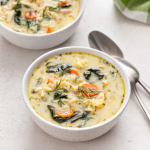 White bowl filled with lemon chicken orzo soup on a countertop.