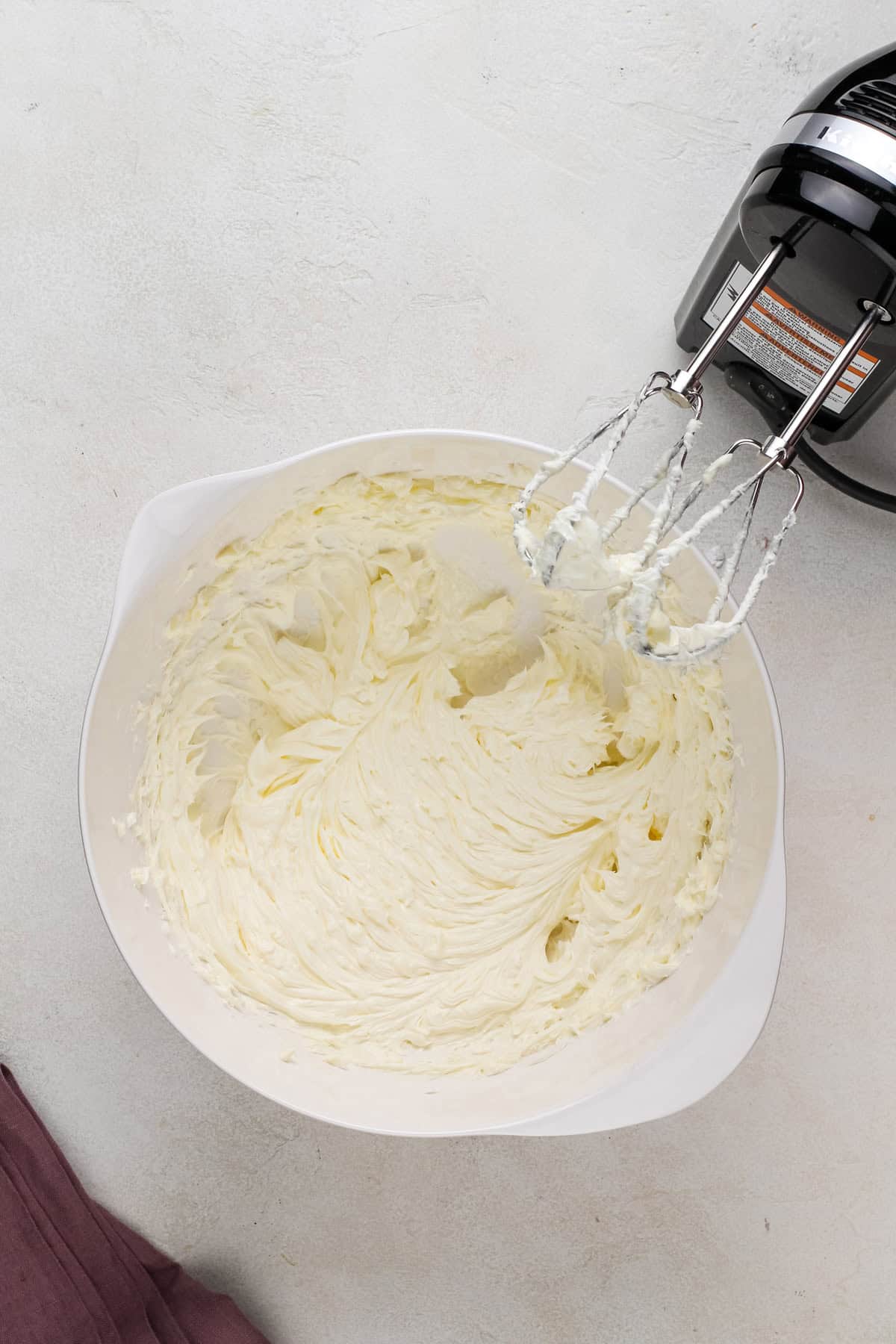 Softened butter whipped with an electric mixer in a bowl.