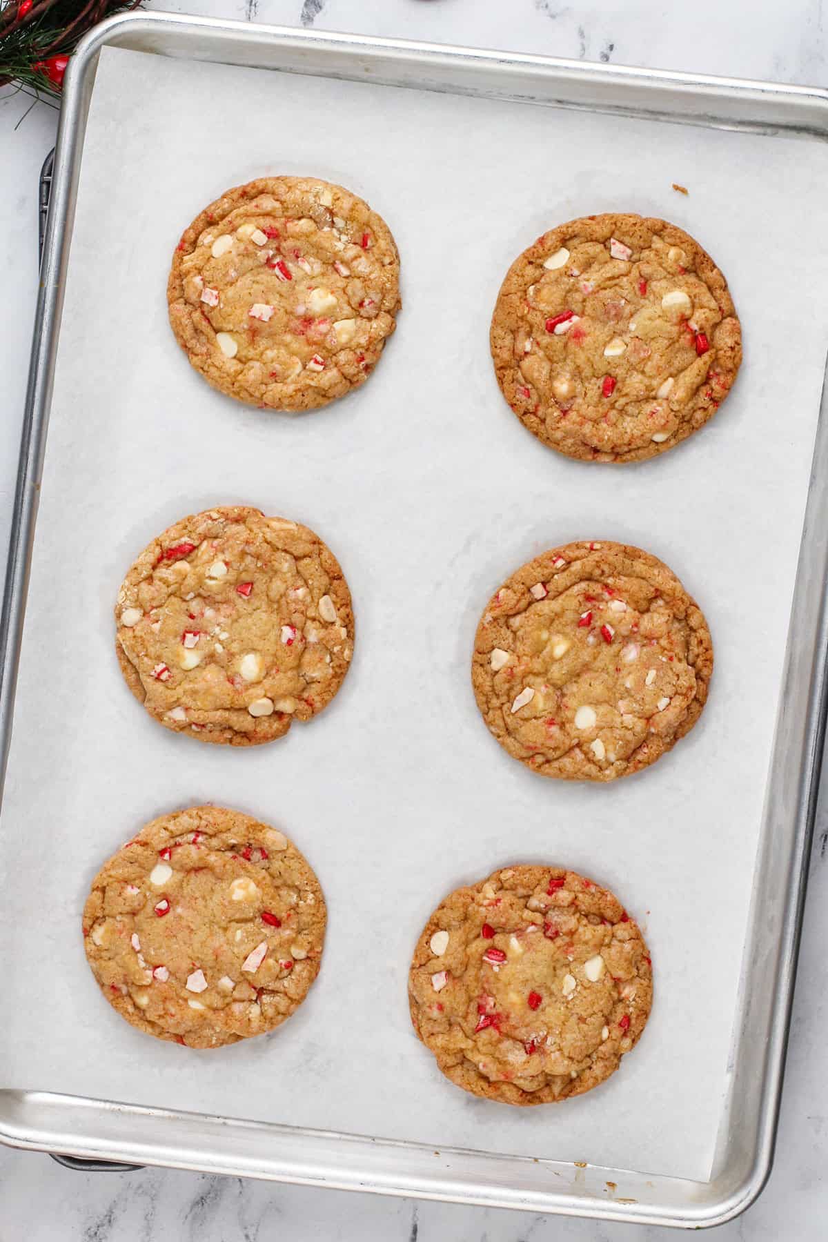 Baked white chocolate chip peppermint cookies on a lined baking sheet.