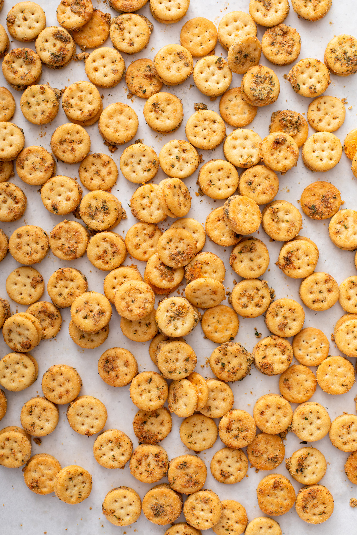 Baked ranch crackers on a parchment-lined baking sheet.