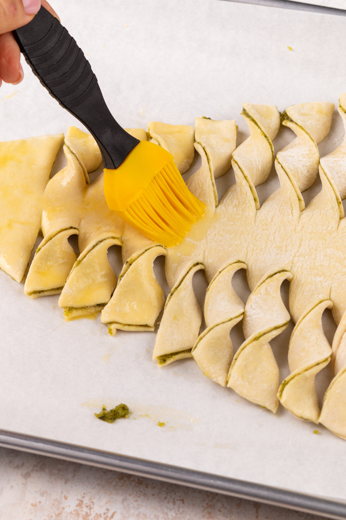 Puff pastry christmas tree being brushed with egg wash.