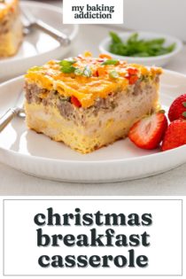 White plate holding a slice of christmas breakfast casserole and fresh strawberries. Text overlay includes recipe name.