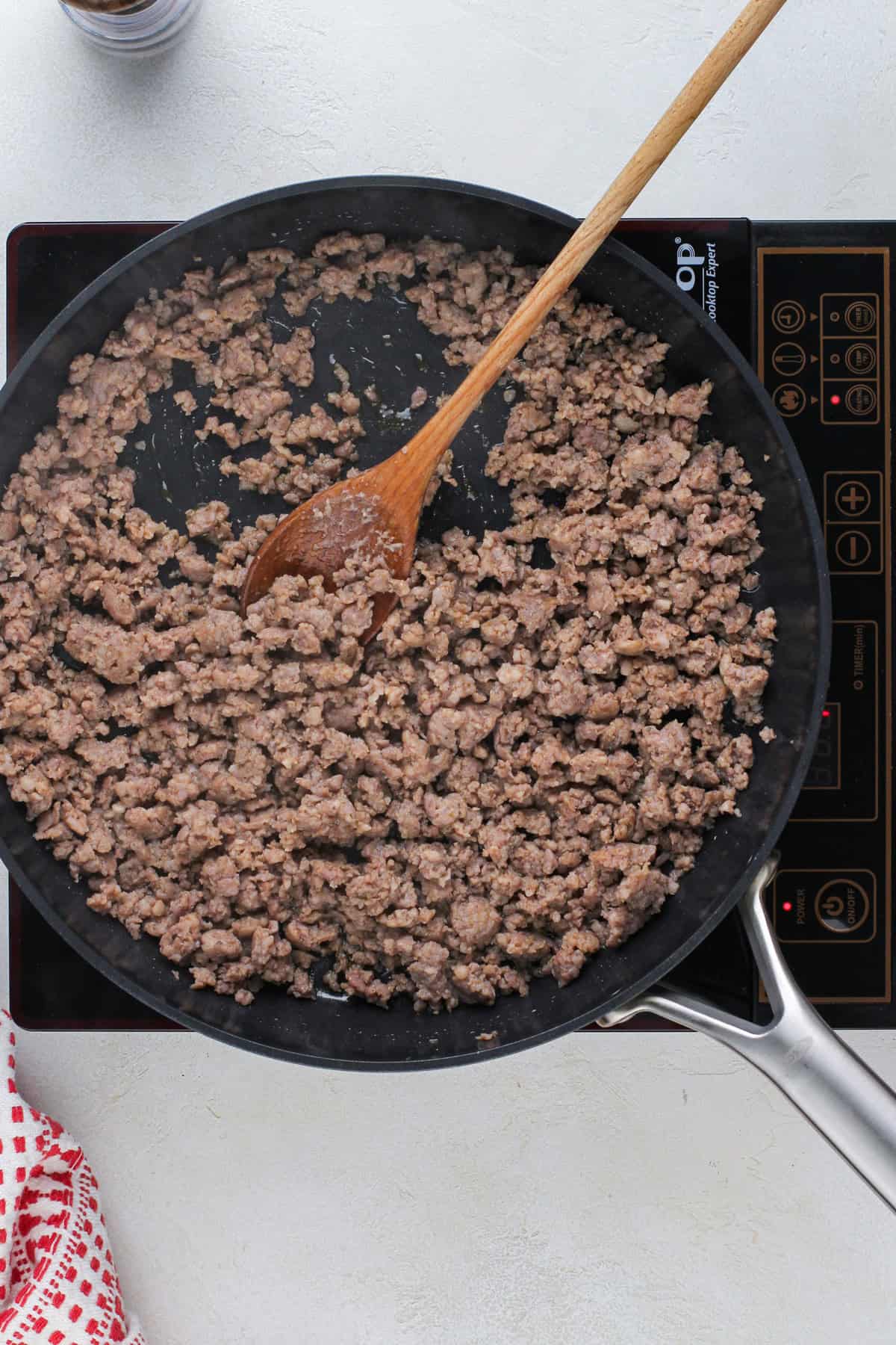 Ground breakfast sausage cooked in a black skillet.